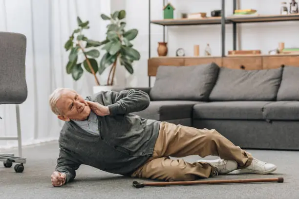 Elderly man who has fallen on the floor, reaching for his neck